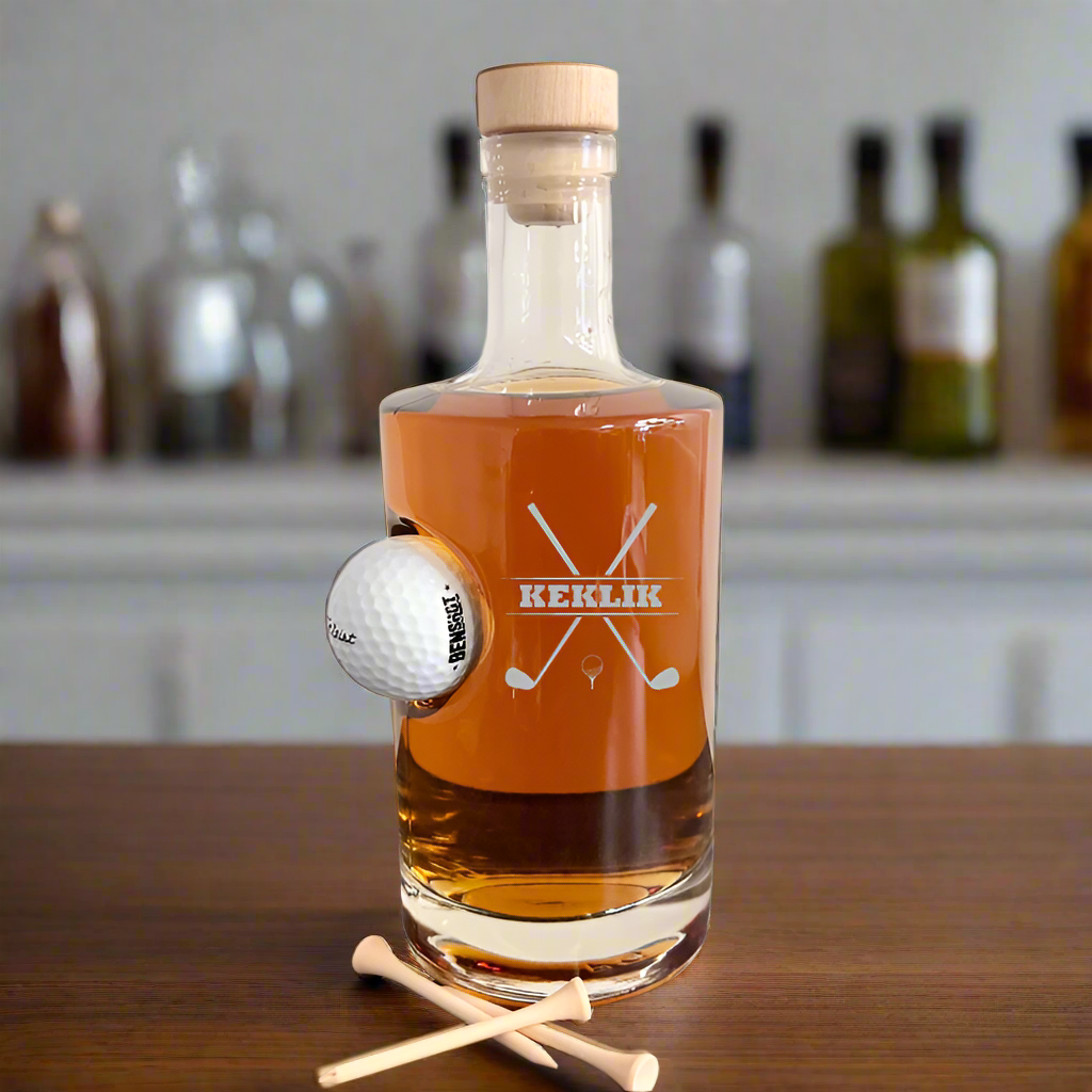 Personalized glass golf decanter with an embedded golf ball, engraved with "KEKLIK" and crossed golf clubs design. 